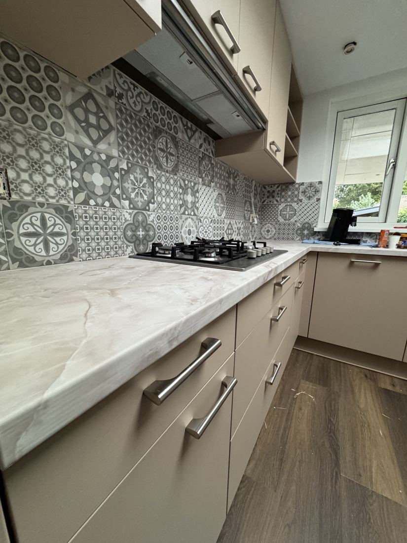 Detail van keukenkastjes in taupe met marmerlook werkblad